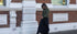 Woman walking on a sidewalk in front of a brick building