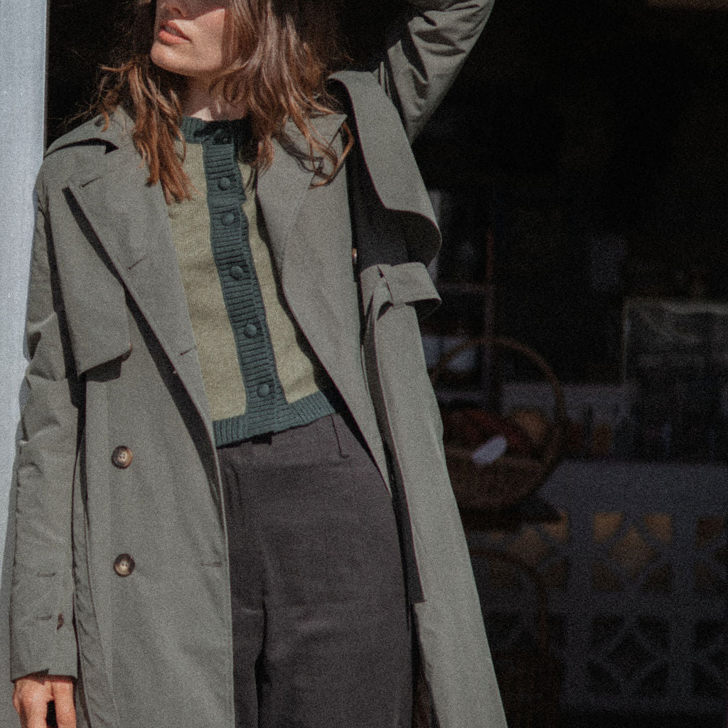 Person wearing a long green coat in an urban setting