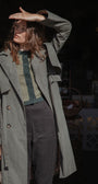 Person wearing a long green coat in an urban setting
