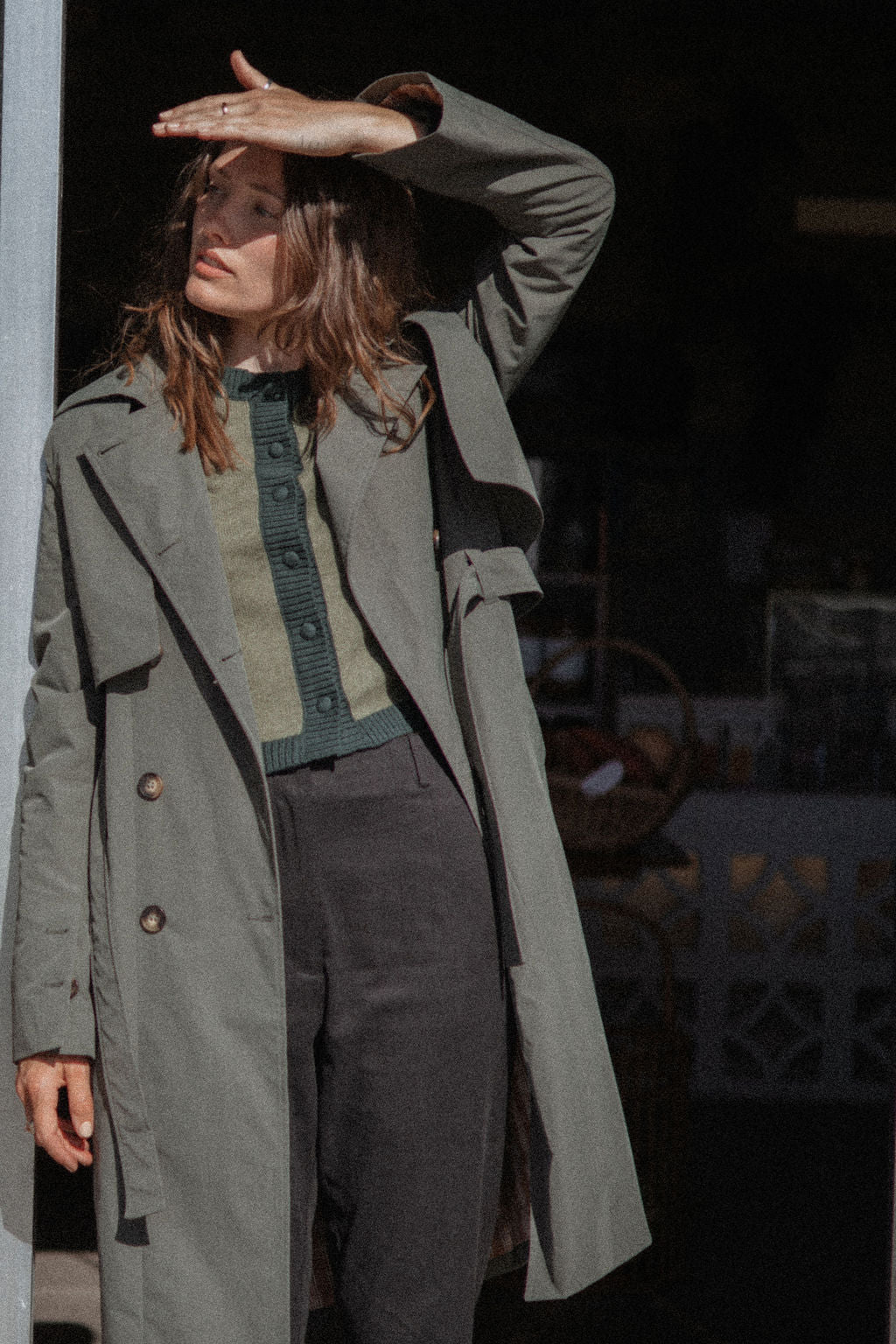 Person wearing a long green coat in an urban setting