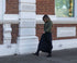 Woman walking on a sidewalk in front of a brick building