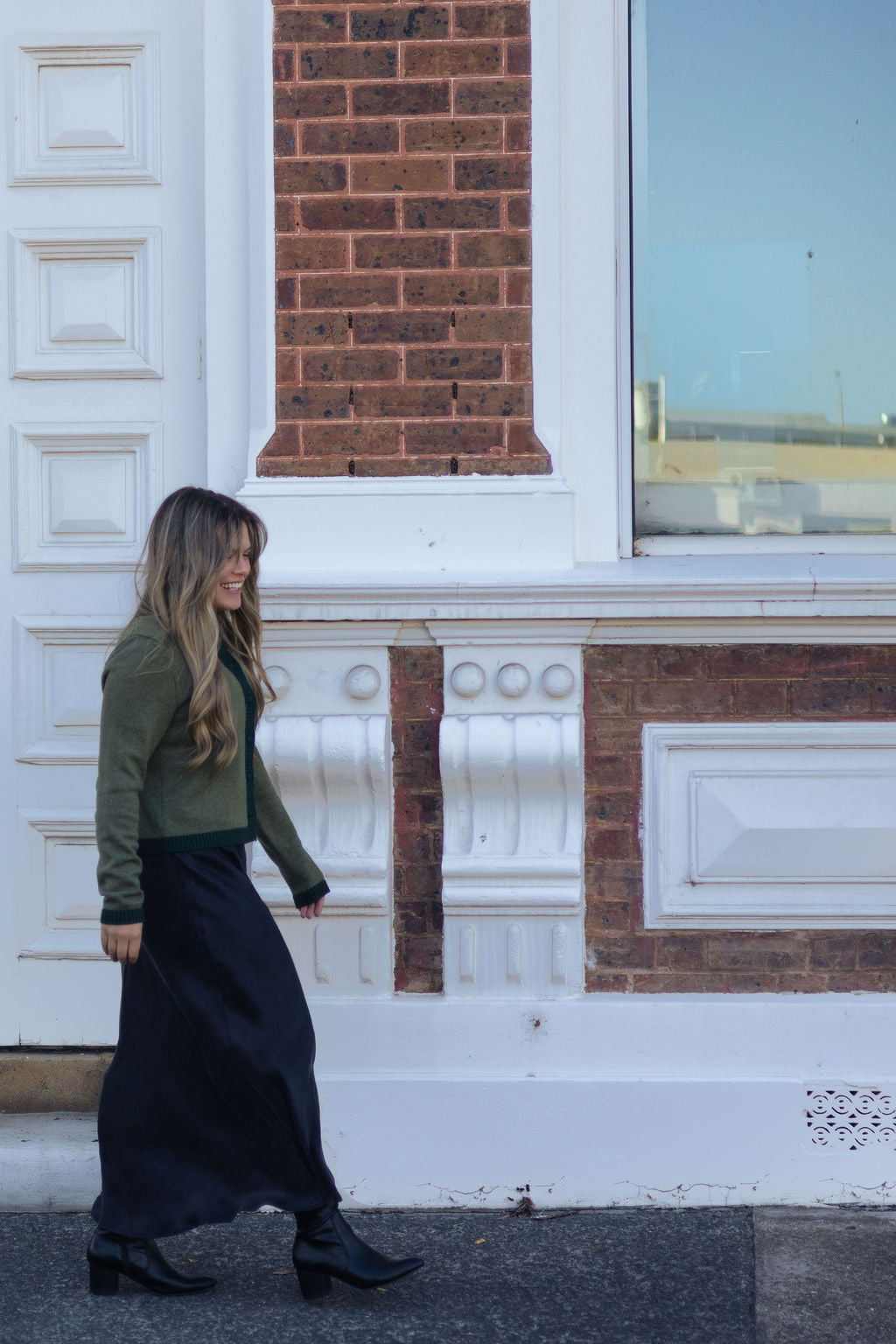 Woman walking in front of a brick building with white decorative elements