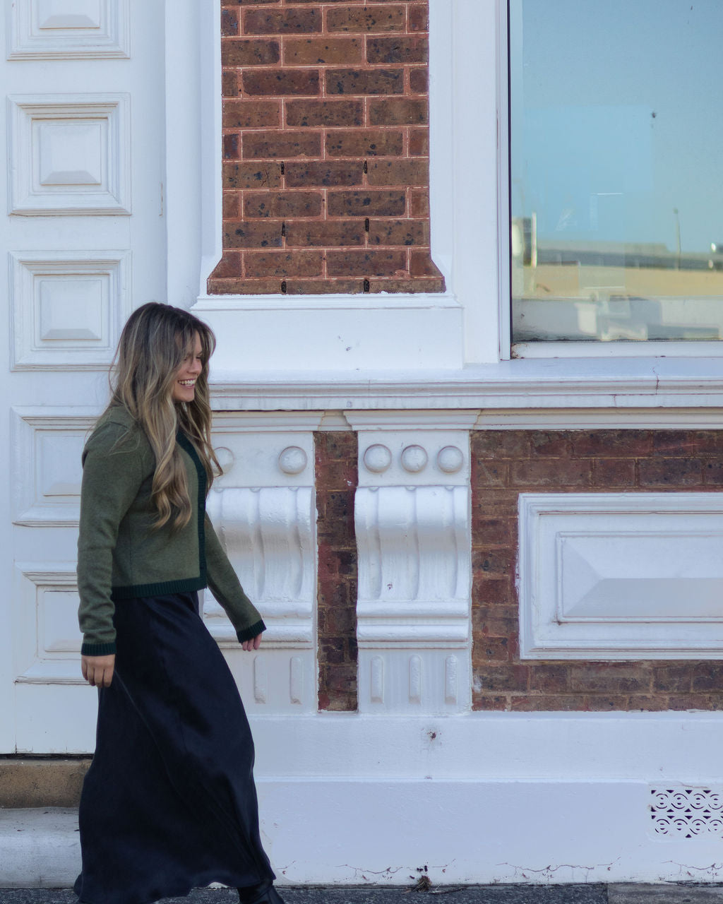 Woman walking in front of a brick building with white decorative elements