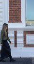 Woman walking in front of a brick building with white decorative elements
