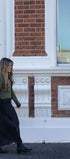 Woman walking in front of a brick building with white decorative elements