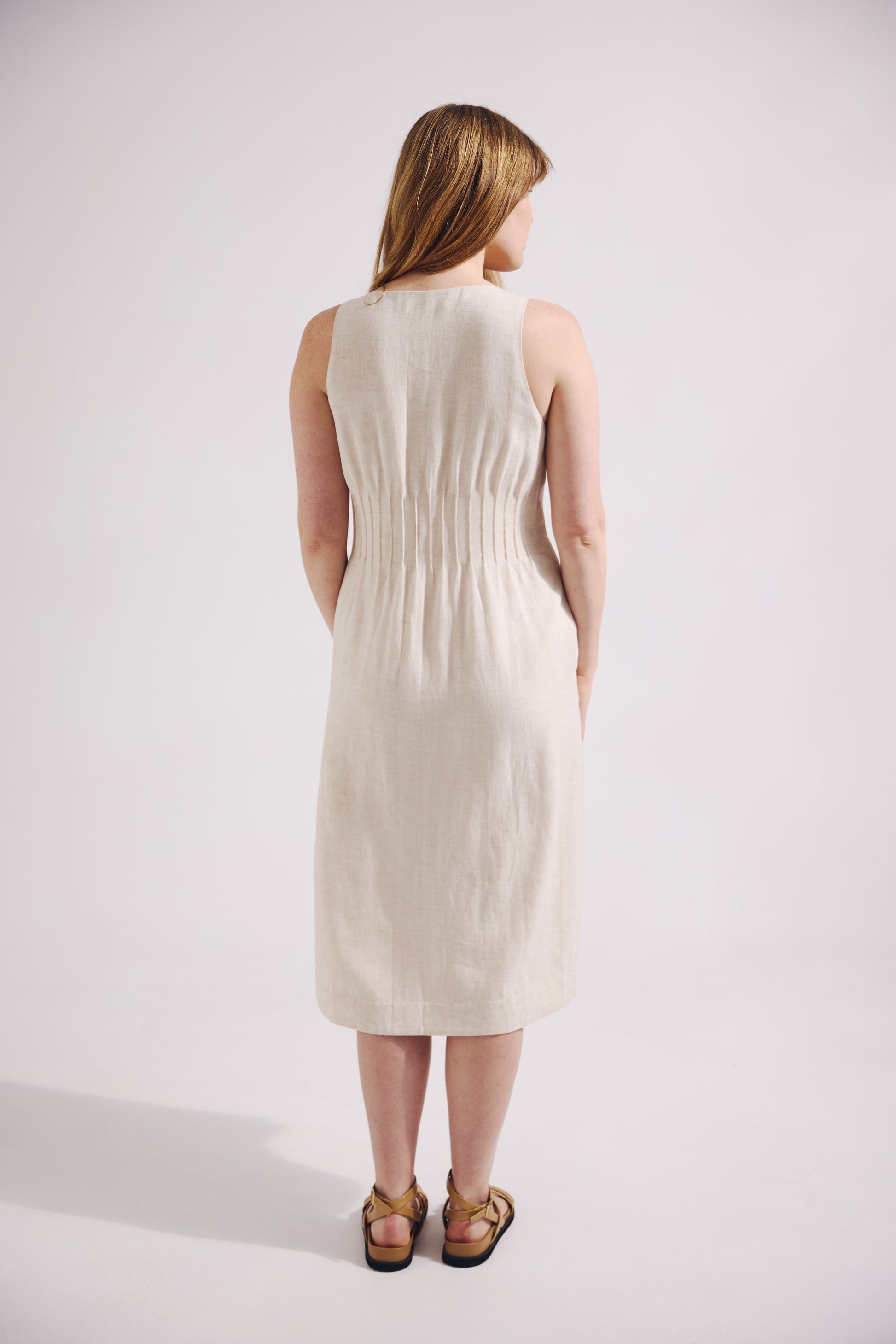 Woman wearing a white sleeveless dress against a plain background