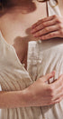Close-up of a person wearing a beige dress with a button detail.