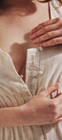 Close-up of a person wearing a beige dress with a button detail.
