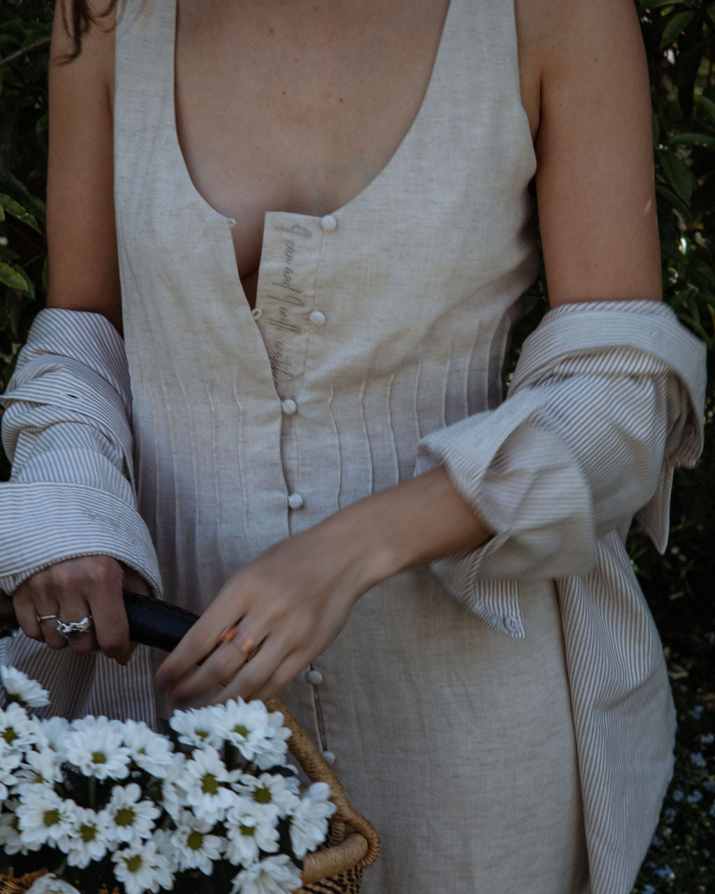 Person holding a basket of white flowers with a blurred natural background