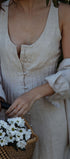 Person holding a basket of white flowers with a blurred natural background