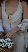 Person holding a basket of white flowers with a blurred natural background