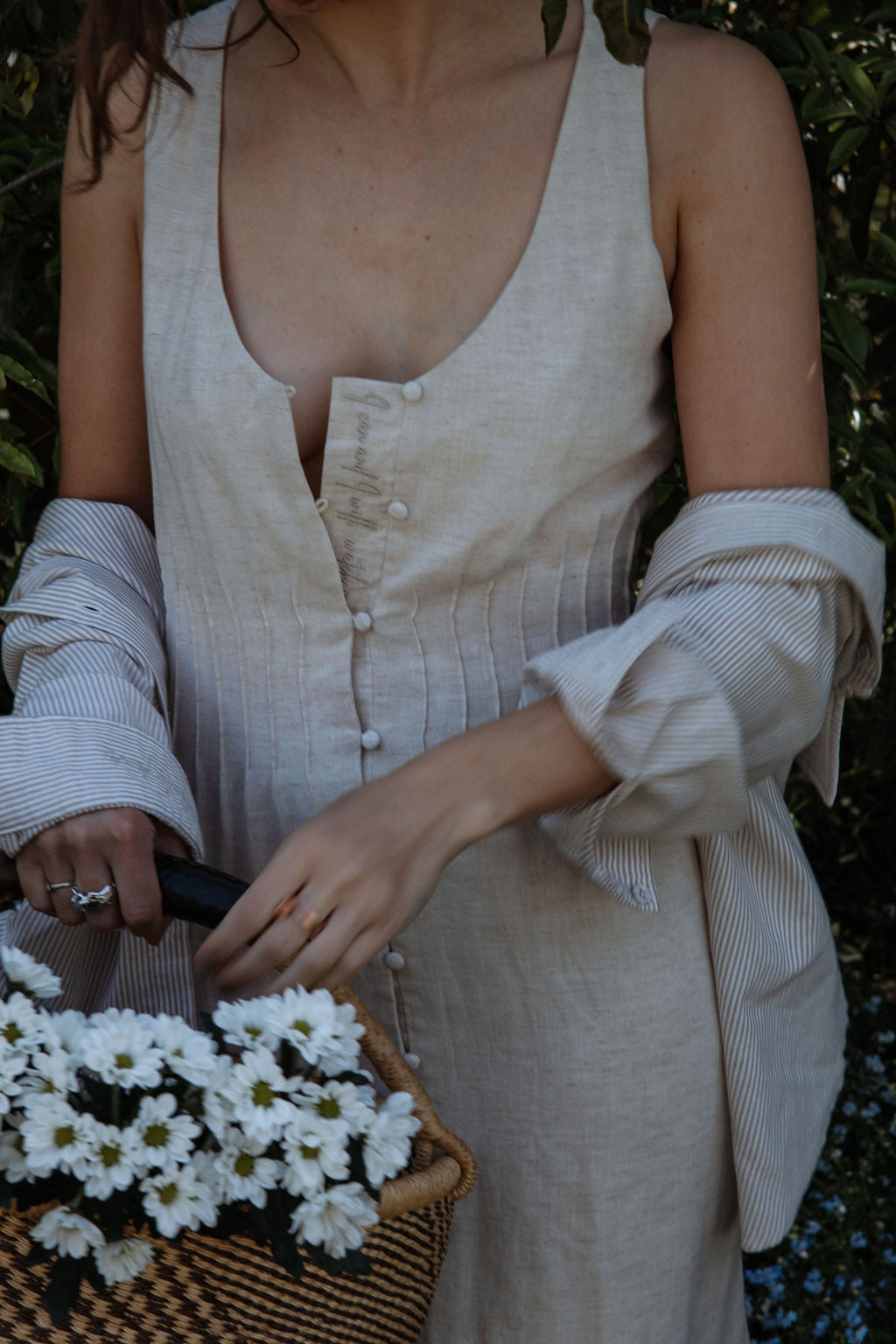 Person holding a basket of white flowers with a blurred natural background