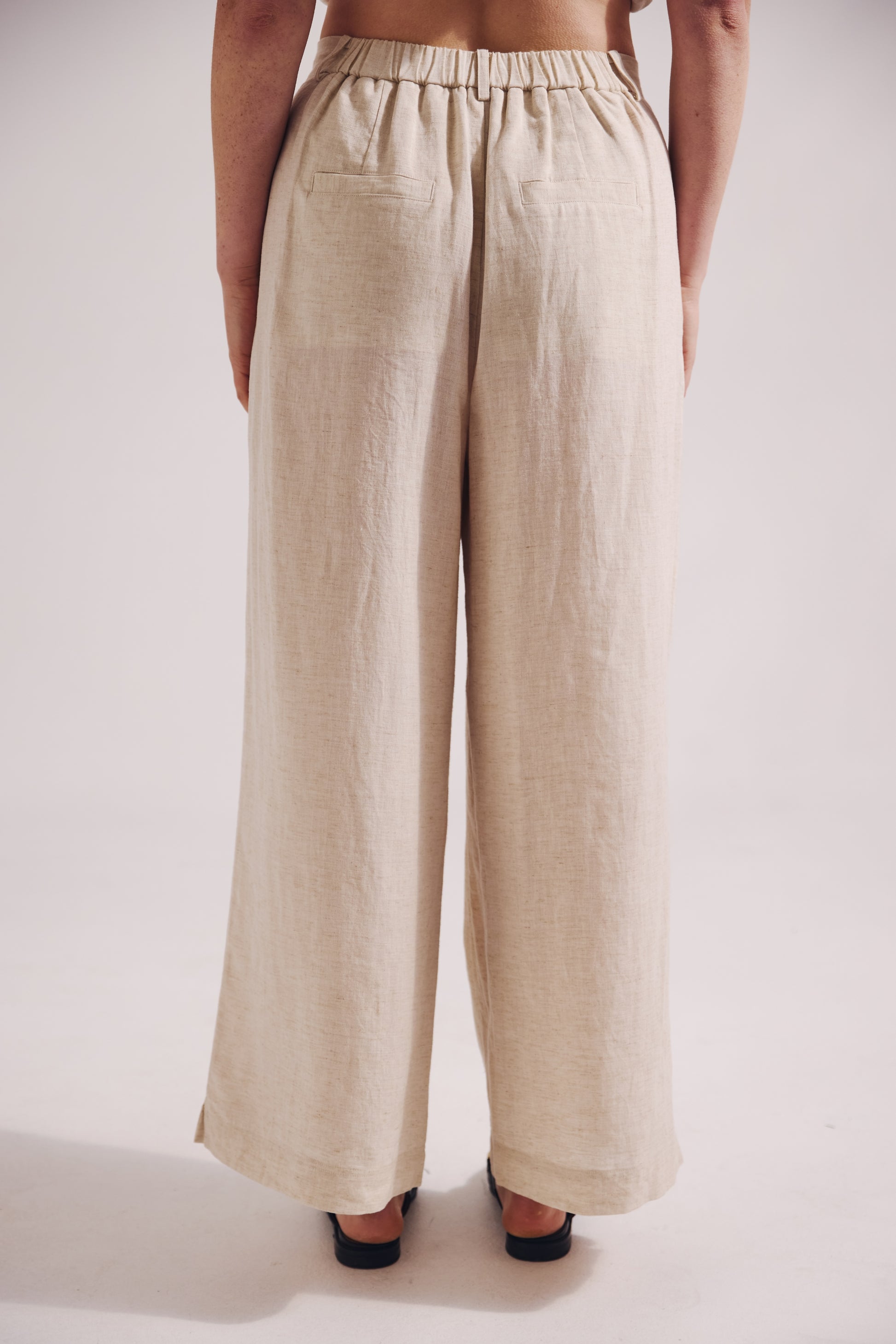 Beige wide-leg pants worn by a person on a white background