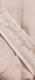 Close-up of beige fabric with 'Sheep Whisperer' embroidery