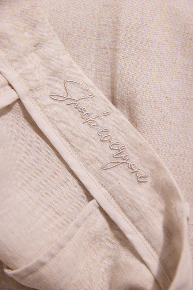 Close-up of beige fabric with 'Sheep Whisperer' embroidery