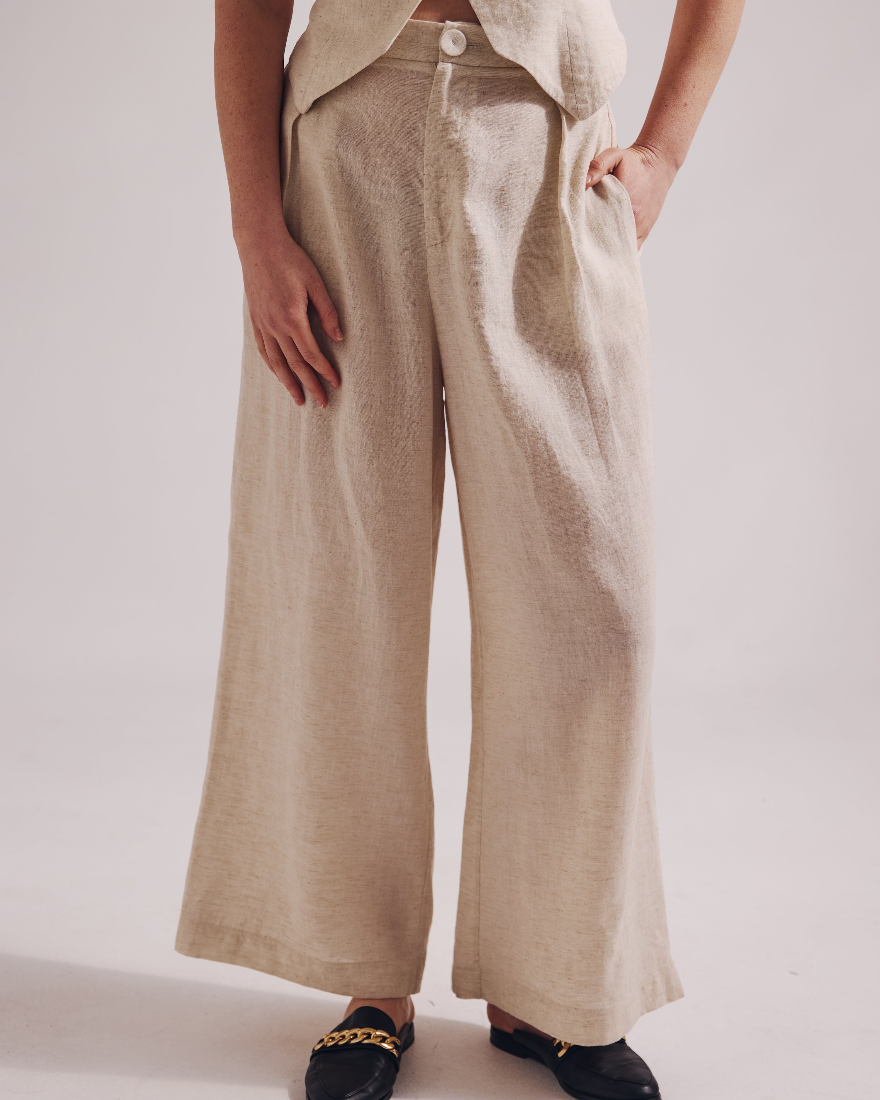 Person wearing beige wide-leg pants on a plain background