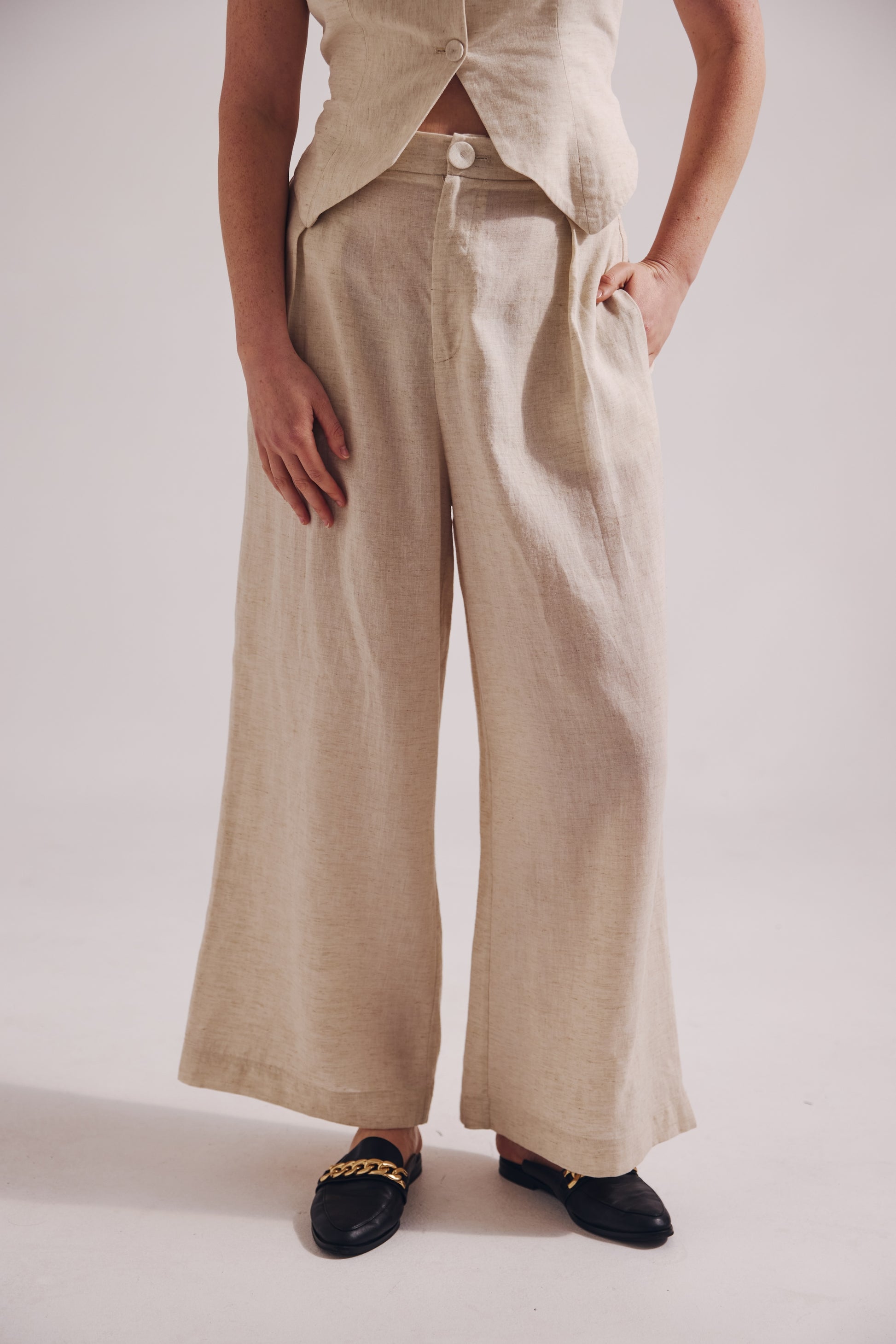 Person wearing beige wide-leg pants on a plain background