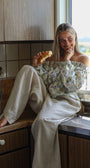 Woman sitting on a kitchen counter eating a croissant
