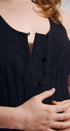 Close-up of a person wearing a black sleeveless top with button details.