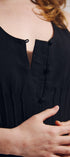 Close-up of a person wearing a black sleeveless top with button details.