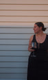 Woman holding a glass of red wine against a light-colored wall.