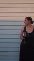 Woman holding a glass of red wine against a light-colored wall.