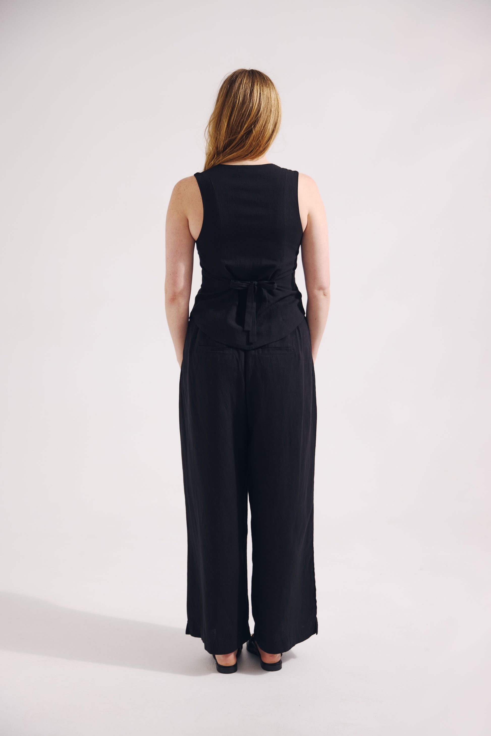 Person wearing a black sleeveless jumpsuit on a white background