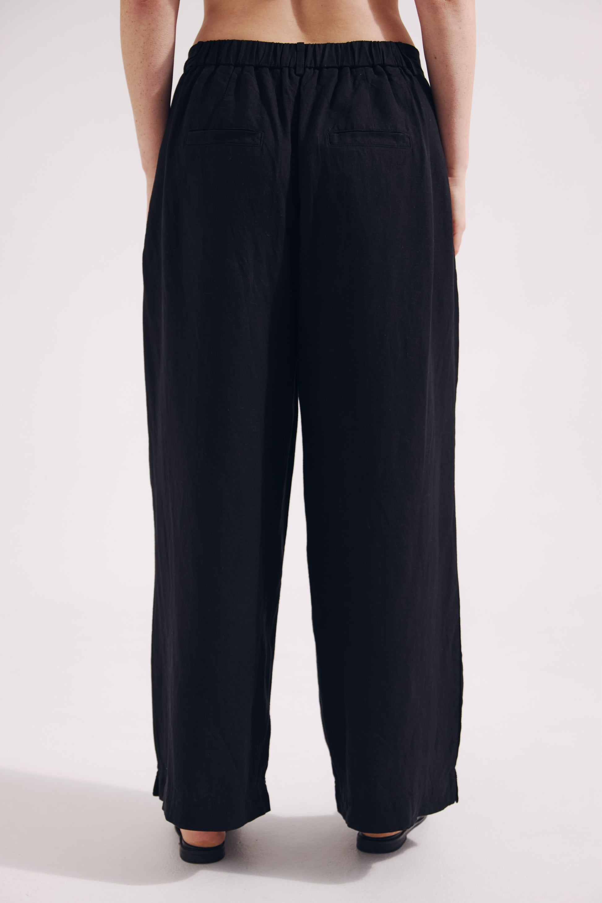 Black wide-leg pants worn by a person on a white background