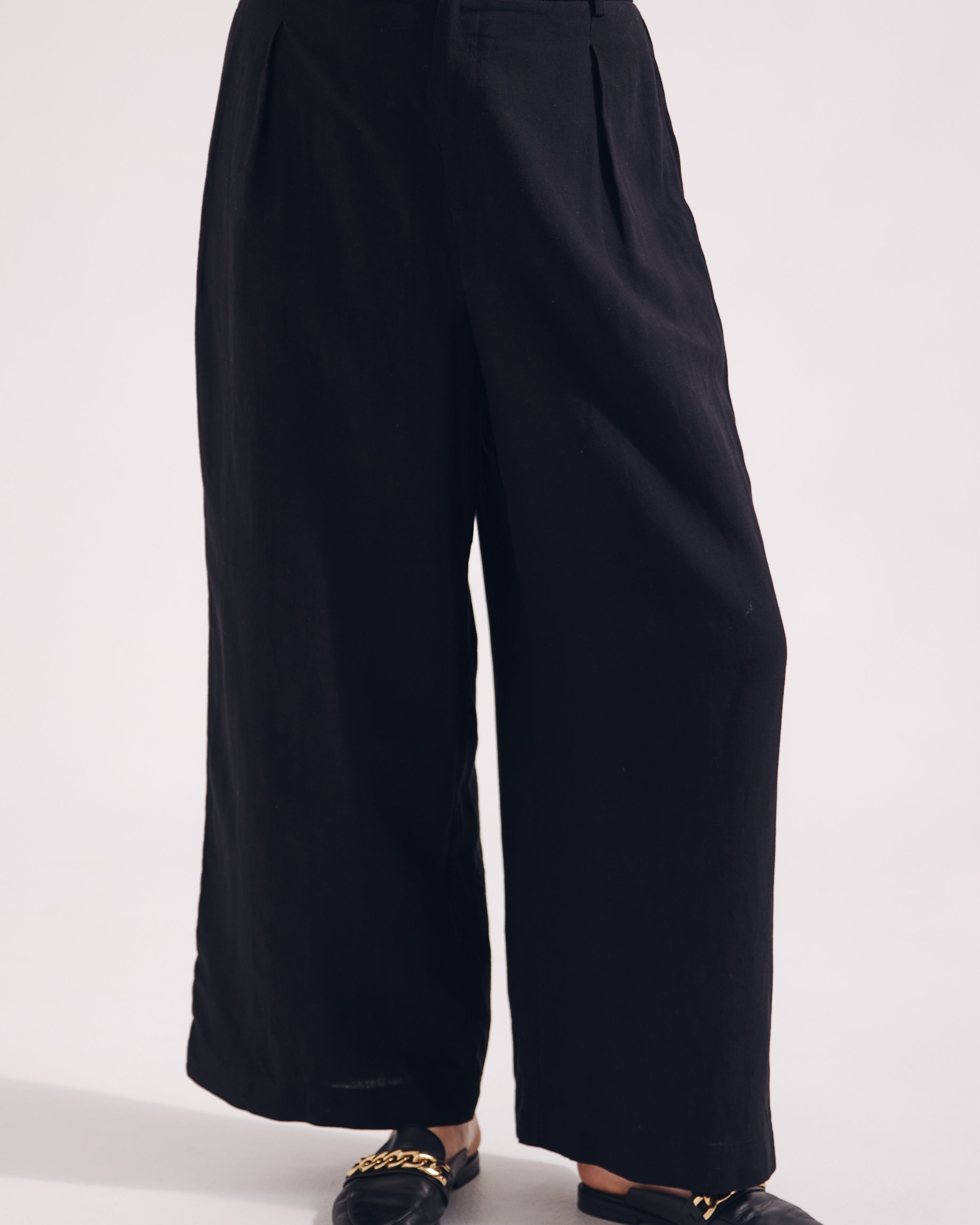 Black wide-leg pants worn by a person on a white background