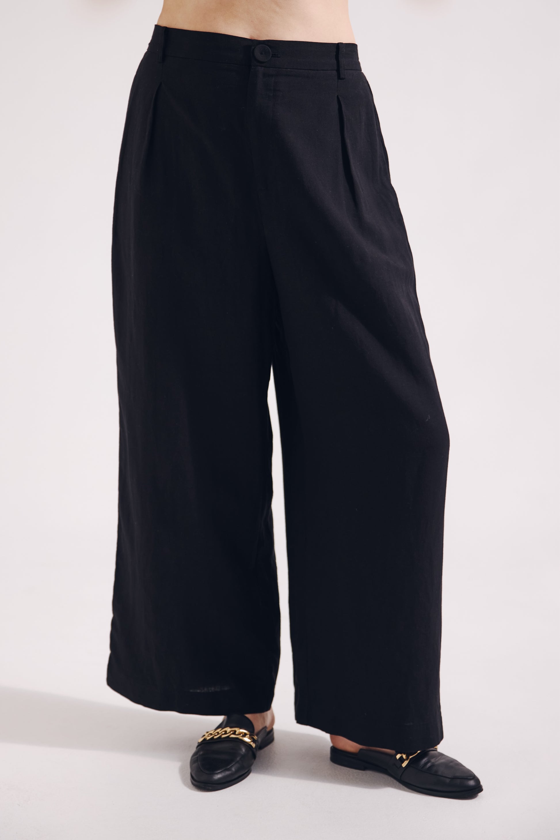 Black wide-leg pants worn by a person on a white background