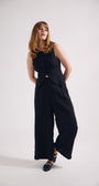 Woman wearing a black sleeveless top and wide-leg pants on a white background