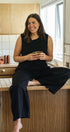 Woman sitting on a kitchen counter holding a cup, smiling.