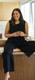 Woman sitting on a kitchen counter holding a cup, smiling.