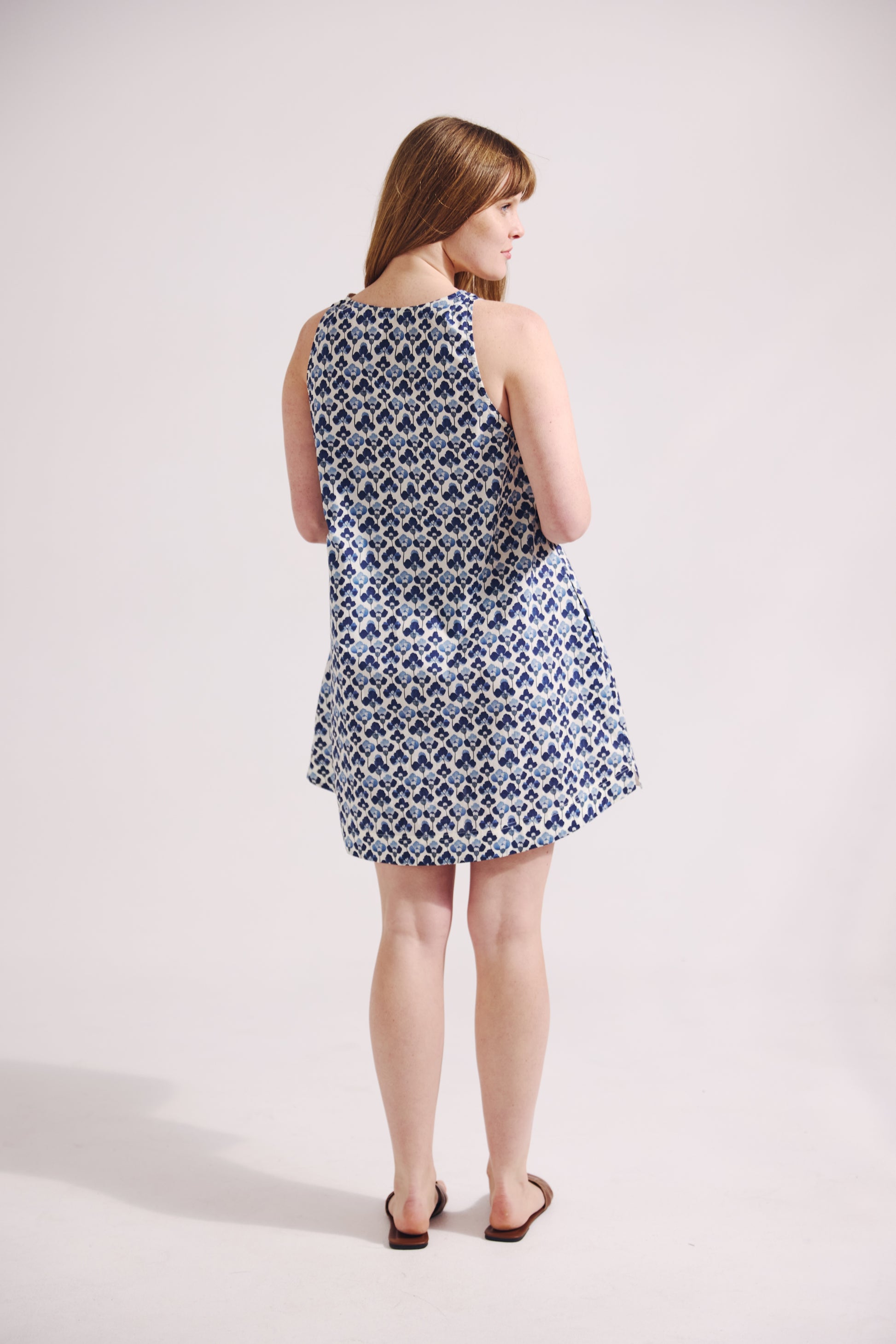 Woman wearing a sleeveless patterned dress on a white background