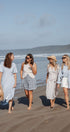 Four women walking on a beach with a clear sky