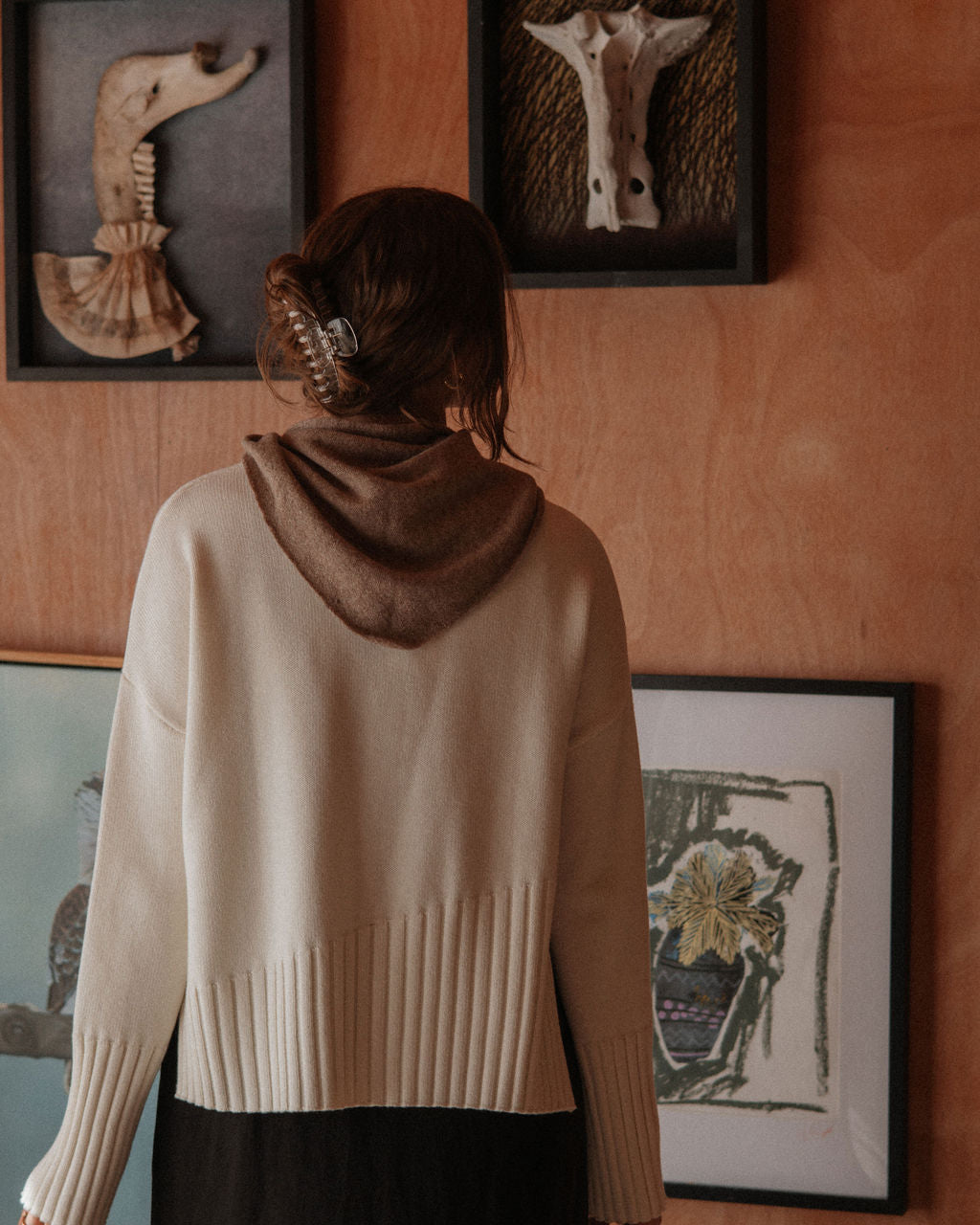 Person wearing a beige sweater standing in front of wall art