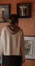 Person wearing a beige sweater standing in front of wall art