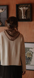 Person wearing a beige sweater standing in front of wall art