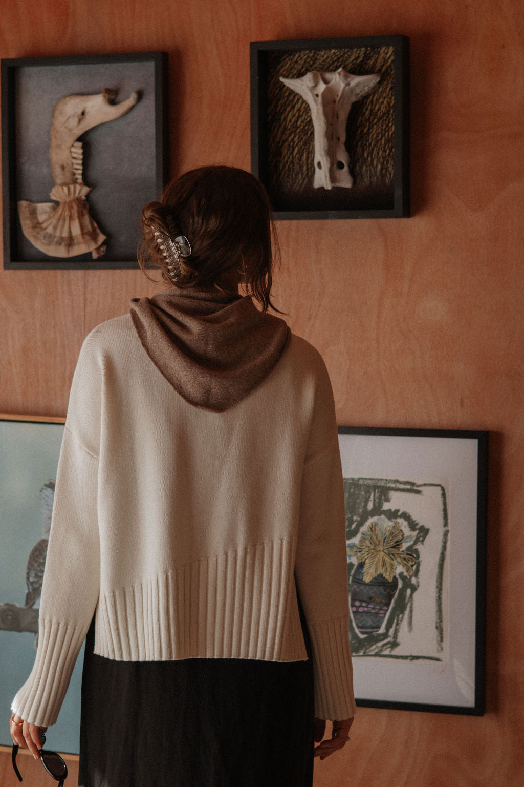 Person wearing a beige sweater standing in front of wall art