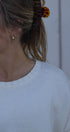 Close-up of a person wearing a white top with embroidery, with a blurred background