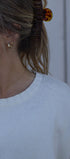 Close-up of a person wearing a white top with embroidery, with a blurred background