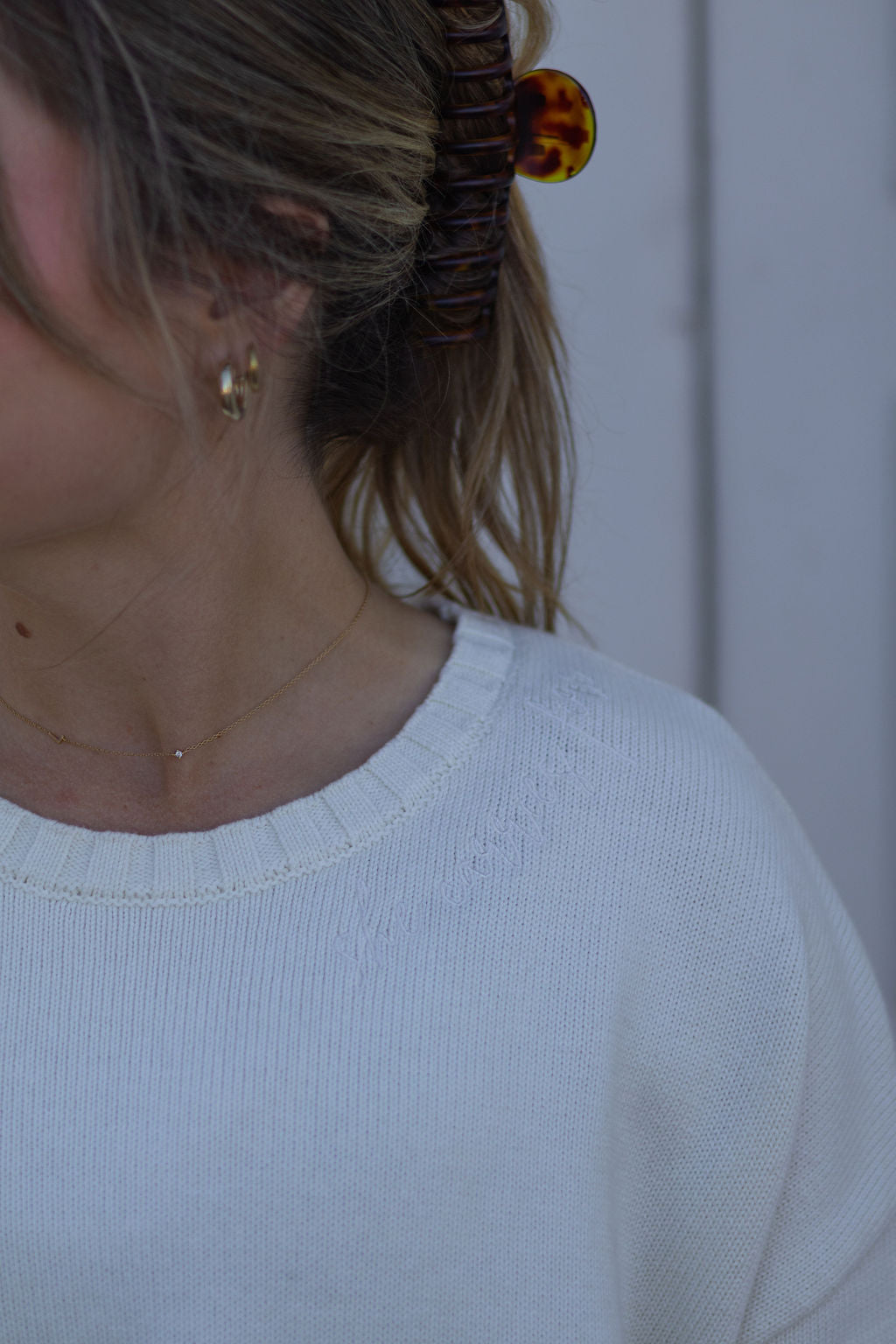 Close-up of a person wearing a white top with embroidery, with a blurred background