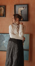Woman standing in front of a wall with framed artwork