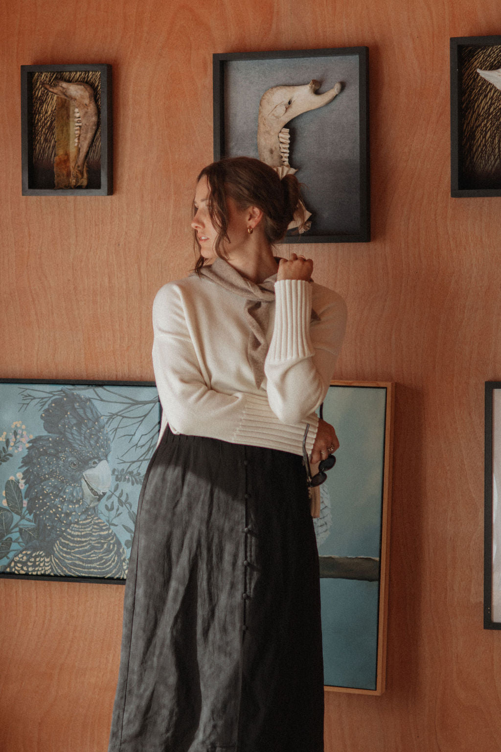 Woman standing in front of a wall with framed artwork