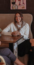 Woman sitting at a table in a cozy cafe, smiling.