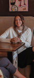 Woman sitting at a table in a cozy cafe, smiling.