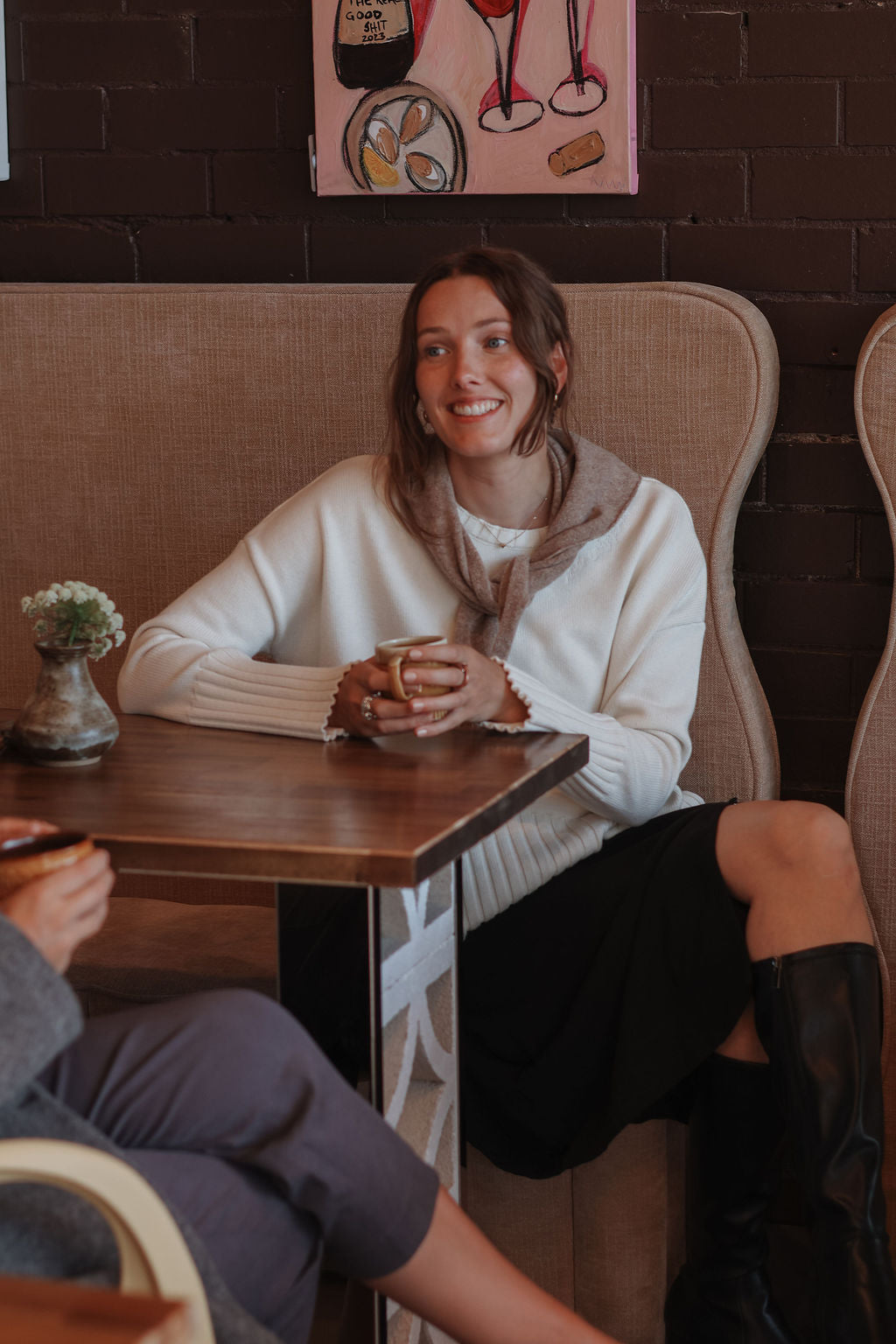 Woman sitting at a table in a cozy cafe, smiling.