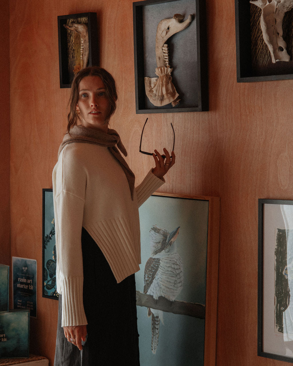 Woman standing in a room with framed animal skeletons on the wall