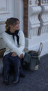 Woman sitting on steps wearing a white sweater and dark blue pants, with a basket nearby.