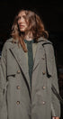 Woman wearing a long green coat with a dark background